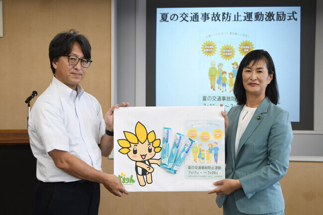 写真：座間市長（写真右）が同協議会構成団体代表　市自治会総連合会の上坂さん（写真左）に啓発物品を手交