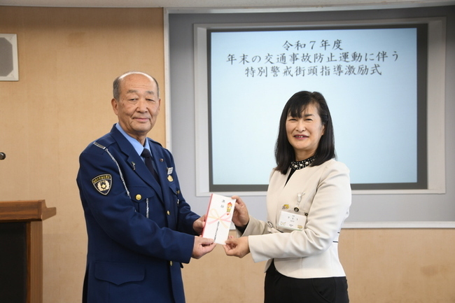 写真：激励金を交付する市長（右）と激励金を受け取る市交通指導員協議会くさなぎ会長（左）
