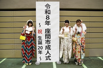写真：令和8年座間市成人式～祝生誕20年～と書かれた立て看板の前で記念撮影をする振袖姿の女性3人