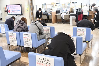 写真：職員の指示に従って姿勢を低くして頭を守る来庁者たち