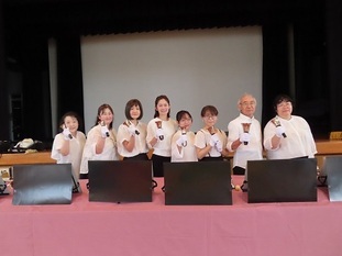 写真：ハンドベルを持った女性7人と男性1人が並んでいます。