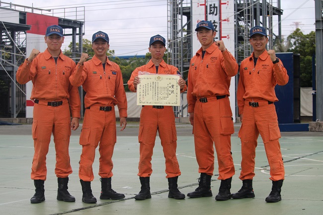 写真:市消防本部隊員5人が並び、中央の1人が表彰状を掲げる様子