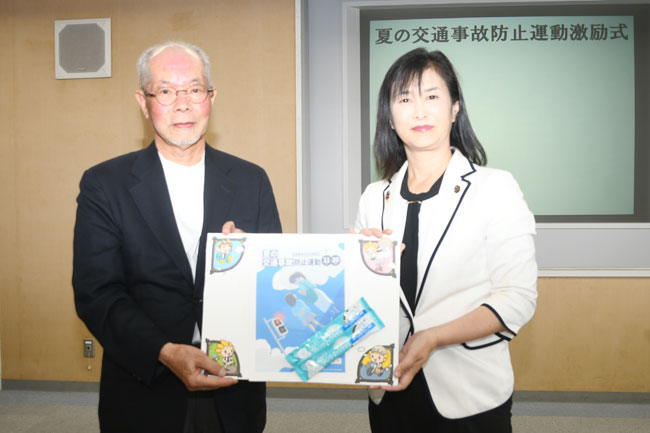 写真：市長（右）が市交通安全対策協議会代表のおいかわさん（左）に啓発物品を手交する様子