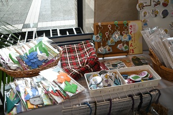 写真:販売商品(ざまりんが書かれた缶バッジやストラップ、花の形に折られた折り紙など)