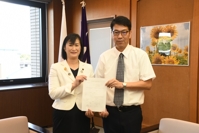 写真:(左から)市長、いとう たけひろさんが支援措置決定通知書を持ち、並ぶ様子